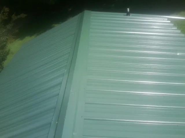 New green metal panels meeting at the ridge of a roof — Flat Roof Repair work by our crew in Woodridge