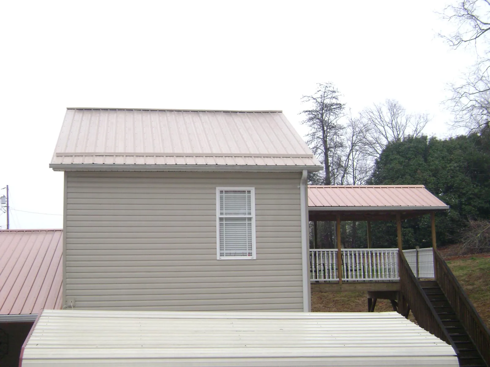 Tan metal roofs on a two story addition and attached porch, from a Roof Replacement job in Woodridge