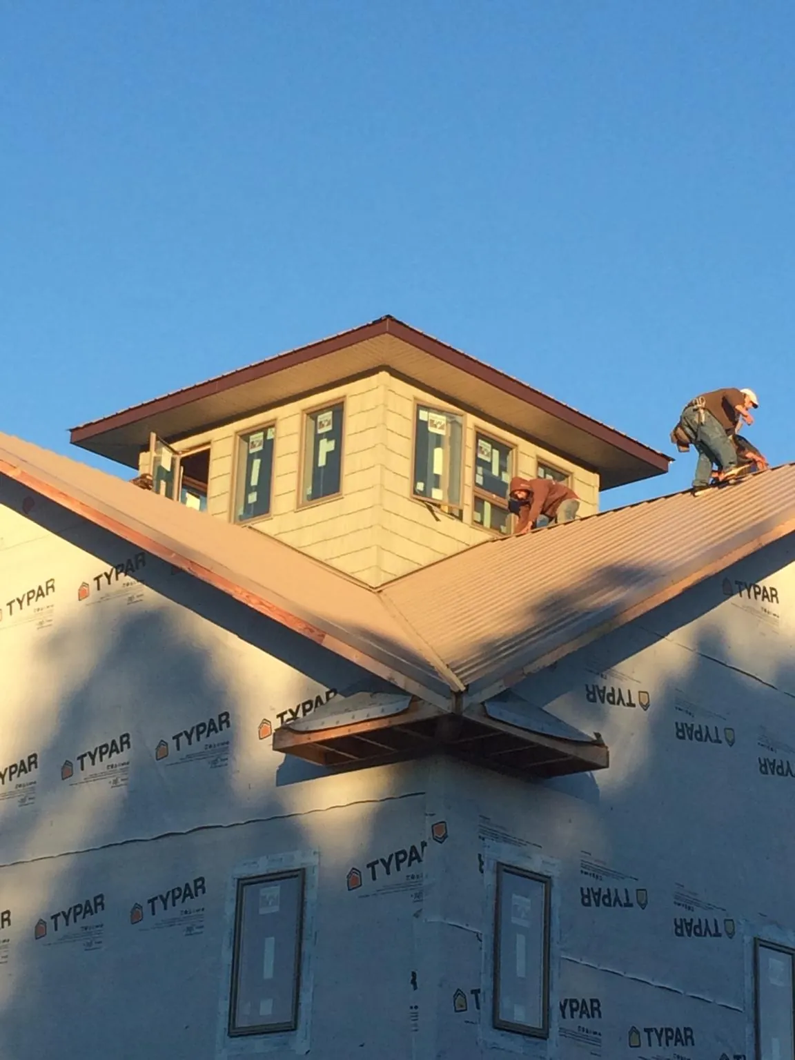 Roofers working around a rooftop cupola on a new metal roof at sunset — Roof Waterproofing in Woodridge by Roofing Brothers